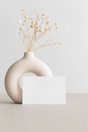 White business card mockup 85x55mm with a gypsophila decoration on the beige table.の写真素材