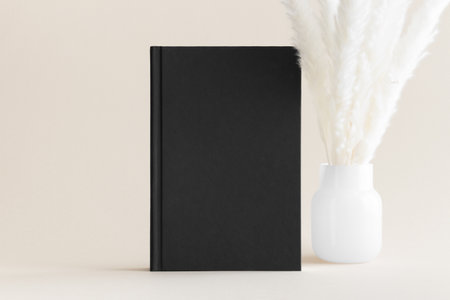 Black book mockup with a pampas decoration on the soft yellow background.の写真素材