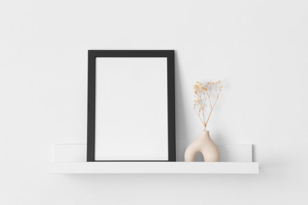 Black frame mockup with a gypsophila decoration on the wall shelf.
