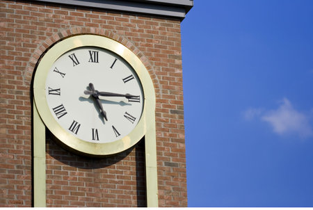 it's 5 oclock somewhere but it's 5:15 on my clock on a brick tower with a nice blue sky and a small cloudの写真素材