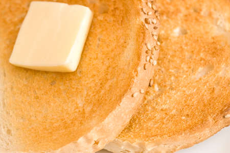 Two slices of toast and a slice of butter on a white plateの写真素材