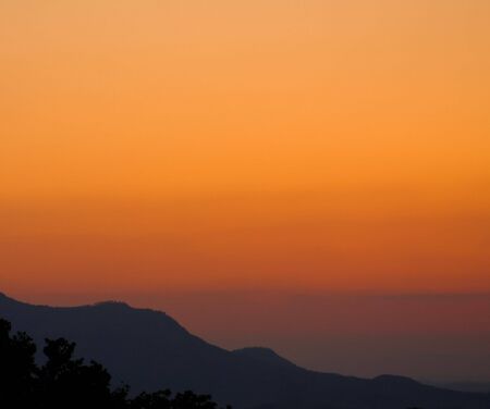 smoky mountains sunset orange skies trees in the foregroundの写真素材