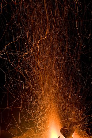 sparks and embers flying up from a campfire at nightの写真素材