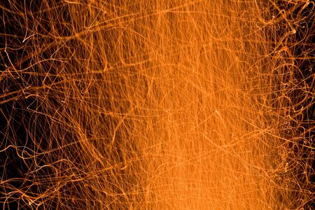sparks and embers flying up from a campfire at nightの写真素材