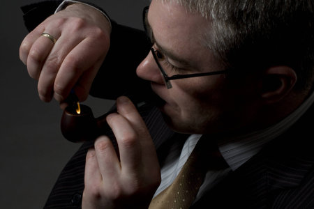 businessman lighting up tobacco pipeの写真素材