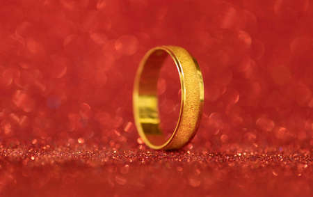 A closeup wedding ring on a red backgroundの写真素材