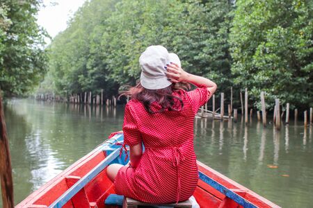 Back of a Senior Lady Tourist on a Wooden Boat on a River. Location is Tung Prong Thong Nature Reserve, Thailand.の写真素材