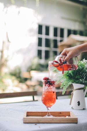 Pouring strawberry, berry and black berry fruit juice drink into glass at gardenの写真素材