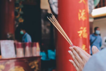An asian woman keep a lotus, candles and incense sticks in hands for praying respect to the buddha statueの写真素材