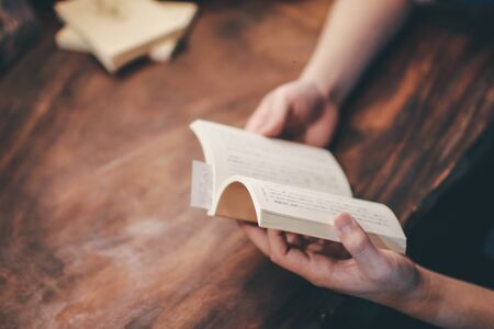 Relaxing moments, Young man opening and reading a book in coffee shop. Relax time on holiday concept travel, Thailand. Color of vintage Tone cozy feeling.の写真素材