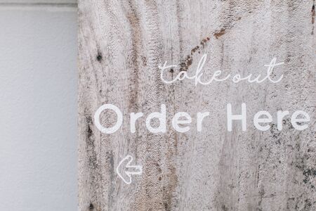 Order here sign and take out on wood wall Wooden order here sign hanging at dimly lit order takeout counterの写真素材