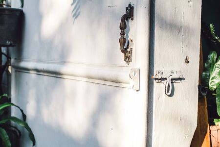 rusted latch lock white door. Front closeup shot of an old plank door of a barn locked with a pad-lock showing old color texture, grains and rust on the latchの写真素材