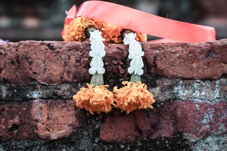 Withered Jasmine Garland or steering flower on old brick in ancient Asian temple outdoor Fresh Orchid Handicraft Steering garland has rose crown flower Jasmine Dahlia Marigold colorful is very beautifulの写真素材