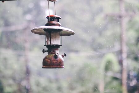 Old lantern in the rain on a background of green.  Beautiful metal lamp in the rain in rain weather. Lantern vintage in the rainの写真素材