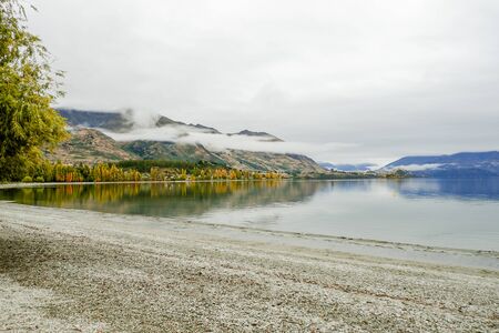 shore of calm lake and mountains Mountain landscape. Rocky shore of mountain lake in rainy in morning shore of a lake with the background mountainsの写真素材
