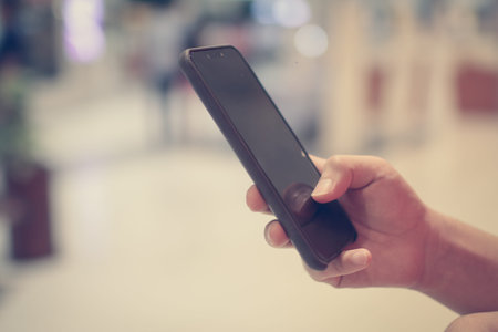 Close up of a man using mobile smart phone with blank copy space screen for your text message or...