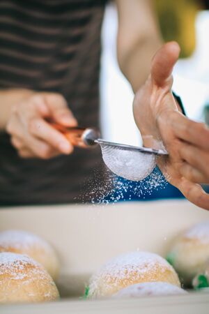 Homemade sweet buns with powdered sugar. Sweet breakfast.Close up view of baker is working.Tasty sweet buns with sweetened condensed milk, Thai tea custard on plate and icing sugarの写真素材
