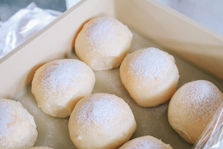 Homemade sweet buns with powdered sugar. Sweet breakfast.Close up view of baker is working.Tasty...