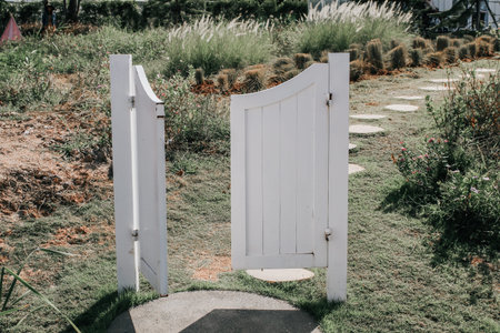 Entrance to the garden of a country house white picket fence gate in front of a beautiful farmland...