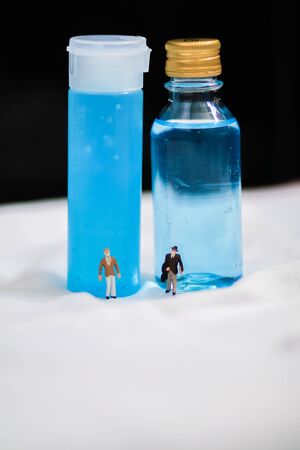 Two mini flicker business man with mask standing in front of alcohol gel and alcohol base hand-washing. Preventive measures against coronavirus ( Sars-CoV-2, Covid-19) infection with antibacterial hand sanitizer gel.の写真素材