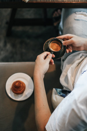 Man in white t-shirt hand holding a hot espresso in black ceramic cup and fresh homemade French...