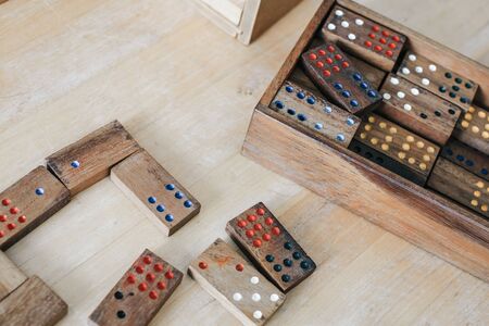 Playing traditional wooden domino game on wooden table background.Family board game, Game night vintage dominos in a row on old rustic table game.Concept of domino effect, chain reaction, risk manage.の写真素材