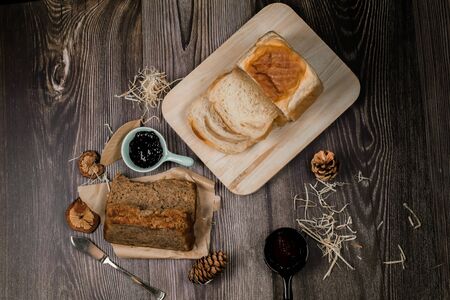 Homemade delicious freshly baked bread classic sweet banana bread sliced with blueberry/strawberry jam and butter knife on a wooden kitchen Table in rustic style.Ideas recipe healthy diet breakfastの写真素材