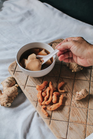 Hand holding spoon eating homemade soy custard in hot ginger syrup eat with with deep fried powder...
