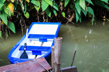 A docking station with blue plastic boat on the water surface still and resting water is ready for people willing to rowの写真素材