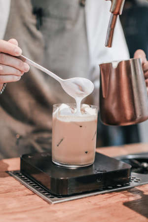 Barista preparing delicious cappuccino : adding foamed milk to espresso on coffee tap counter.の写真素材