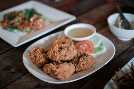 Fried shrimp cake,Thai food name is Tod Mun Goong eat with sweet sauce served on white dish in restaurant.の写真素材