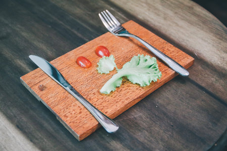 Fresh vegetables make angry face on a cutting board on a light wooden table Tomatoes, lettuce,knife...