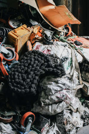 A mix variety garbage of used old rustic mechanic iron and plastic part in the hazy dim factory shallow focus. Scrap parts removed from used cars and machinery.の写真素材