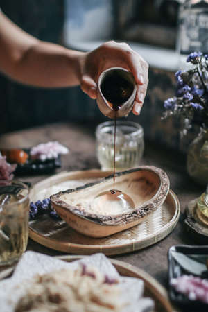 Hand pouring Brown Sugar Syrup into Mizu Shingen Mochi japanese dessert.A Japanese style dessert with decoration. Raindrop Mizu Mochi is a popular dessert in Japanese.の写真素材