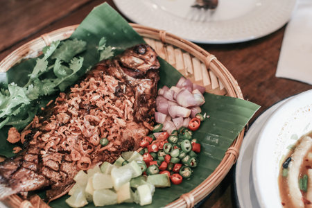 Asian food concept. Deep fried fish, crispy garlic, pepper, decorate with chili, spring onions serve...