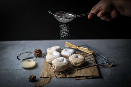 Fresh homemade donuts with powder sugar on the black dark rustic background. Falling powder sugar on donuts Breakfast concept, Selective focus.の写真素材