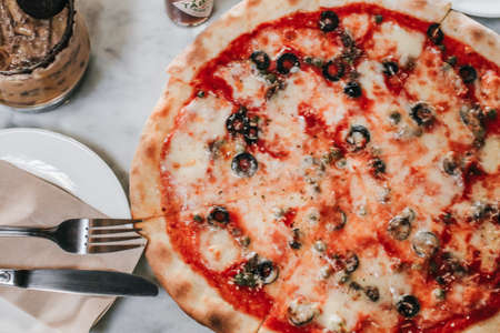 Pizza with Mozzarella cheese, ham, pepper,Tomatoes, and olives. Having party at home, eating pizza and having fun. leisure, food and drinks, people and holidays conceptの写真素材