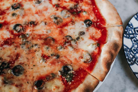 Pizza with Mozzarella cheese, ham, pepper,Tomatoes, and olives. Having party at home, eating pizza and having fun. leisure, food and drinks, people and holidays conceptの写真素材