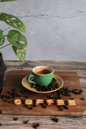 Coffee in a white cup with roasted coffee beans and small English letter crispy bread on a wooden...