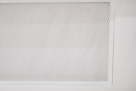 White cement walls and steel window on the side of the building. The window use steel grating as a...