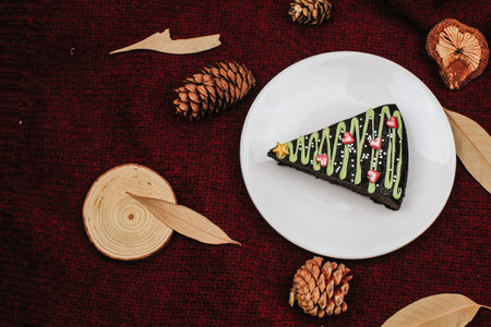 Slice of sweet chocolate cake for Christmas Eve in shape of Christmas Trees with green icing and...
