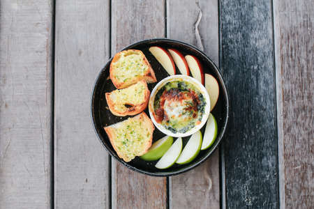 Baked spinach with cheese and garlic bread on wooden table - Italian food style.の写真素材