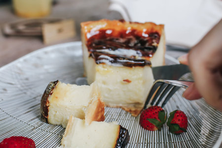 Woman eating Basque burnt cheesecake with Strawberry made with sweetened cream cheese and eggs and...