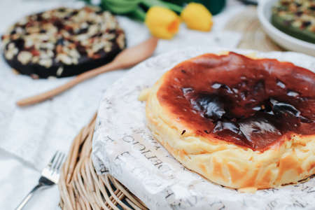 Basque burnt cheesecake with sweetened cream cheese and eggs and cream baked in a crumb crust. A tray of homemade cheesecake on tableの写真素材