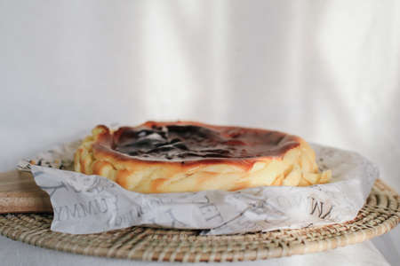 Basque burnt cheesecake with sweetened cream cheese and eggs and cream baked in a crumb crust. A tray of homemade cheesecake on tableの写真素材