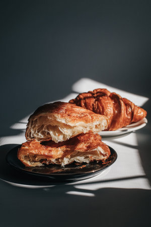 Croissants on a dark background in the morning light, sunlight shadow. Morning breakfast concept....