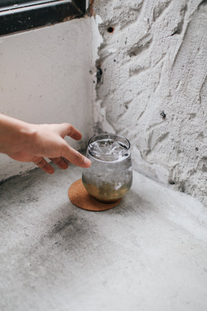 Hands holding freshly cocktails with ice on concrete floor. Summer time vacation concept.の写真素材