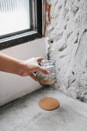 Hands holding freshly cocktails with ice on concrete floor. Summer time vacation concept.