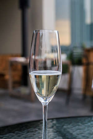 Glass of white wine on table in outdoor cafe, closeup. Cheerfully celebrate outdoors with glasses of white wine, People having dinner in restaurant.の写真素材