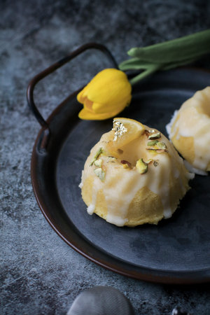 Lemon cake with sugar sweet icing on yellow and black background. Cake with citrus, poppy,...